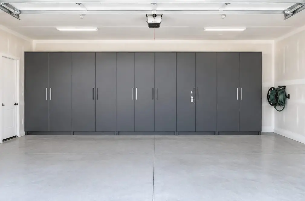 Illustration: a two-car garage in Menifee, CA with one wall of dark gray steel cabinets, two locking doors, a hose reel and a clear concrete floor